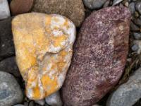 Ockerfarbener Stein mit weißen Einschlüssen neben dunkelbraunem Konglomeratstein